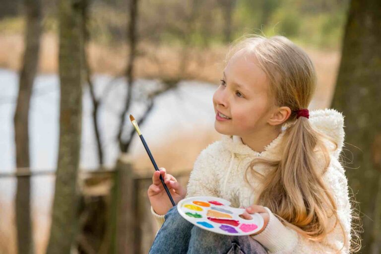 Girl painting with a brush and palette in her hand / Freepik