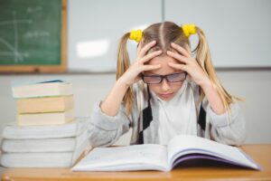 Девочка сидит за учебником/ Freepik