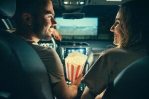 A young couple sitting in a car with popcorn.