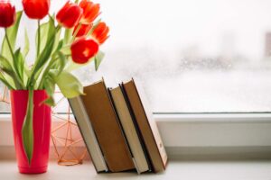 Books on the windowsill with tulips / Freepik