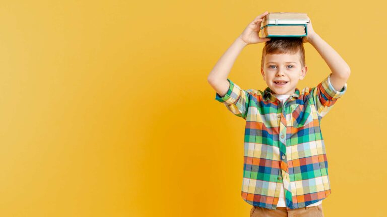 Boy holding a stack of books on his head / Freepik
