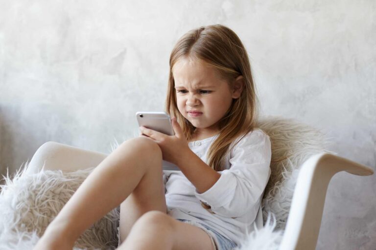 Girl frustrated, looking at smartphone / Freepik
