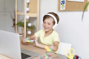Мальчик сидит за ноутбуком в наушниках / Freepik