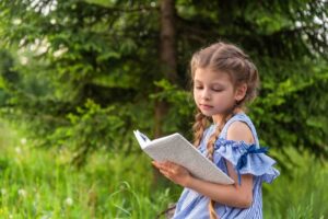 Девочка читает книгу в лесу / Freepik