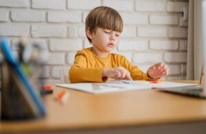 A boy sitting at a desk with a pen / Freepik