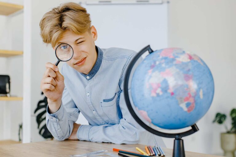 A guy studying geography sitting next to a globe / Freepik