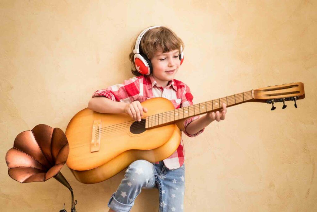A child listening to music at home. Hipster child with retro vintage acoustic guitar / Freepik