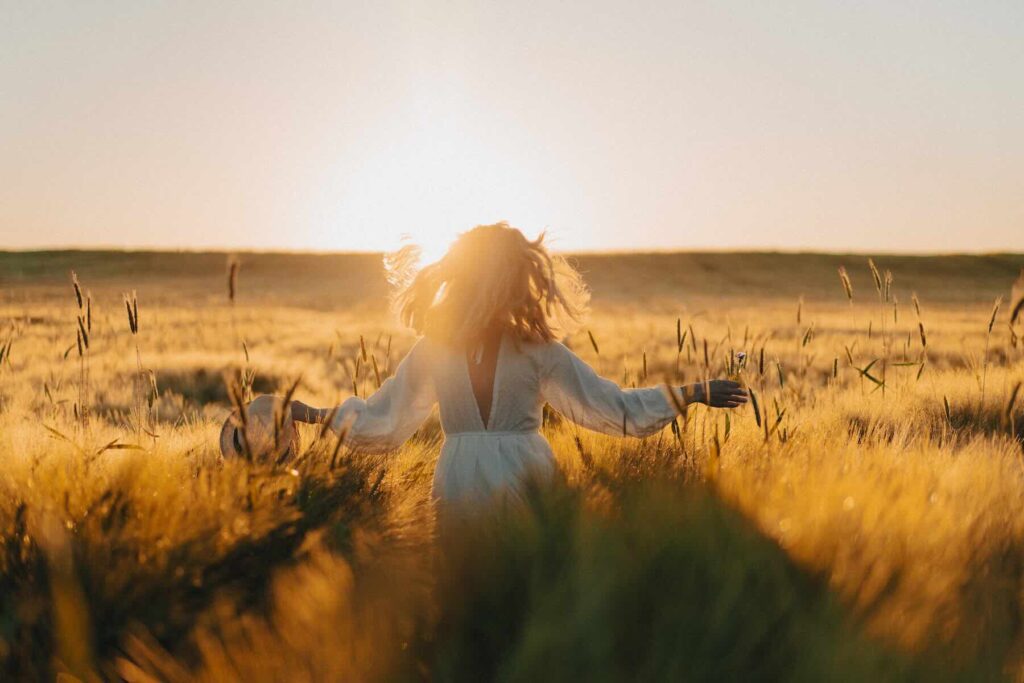 A young beautiful woman with long blonde hair in a white dress in a wheat field in the early morning at dawn. Summer is the time of dreamers, waving hair, the woman is running through the field in the sunlight. travel / Freepik