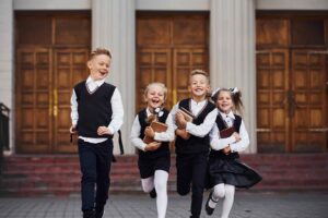 A group of children in school uniforms running together in the street / Freepik