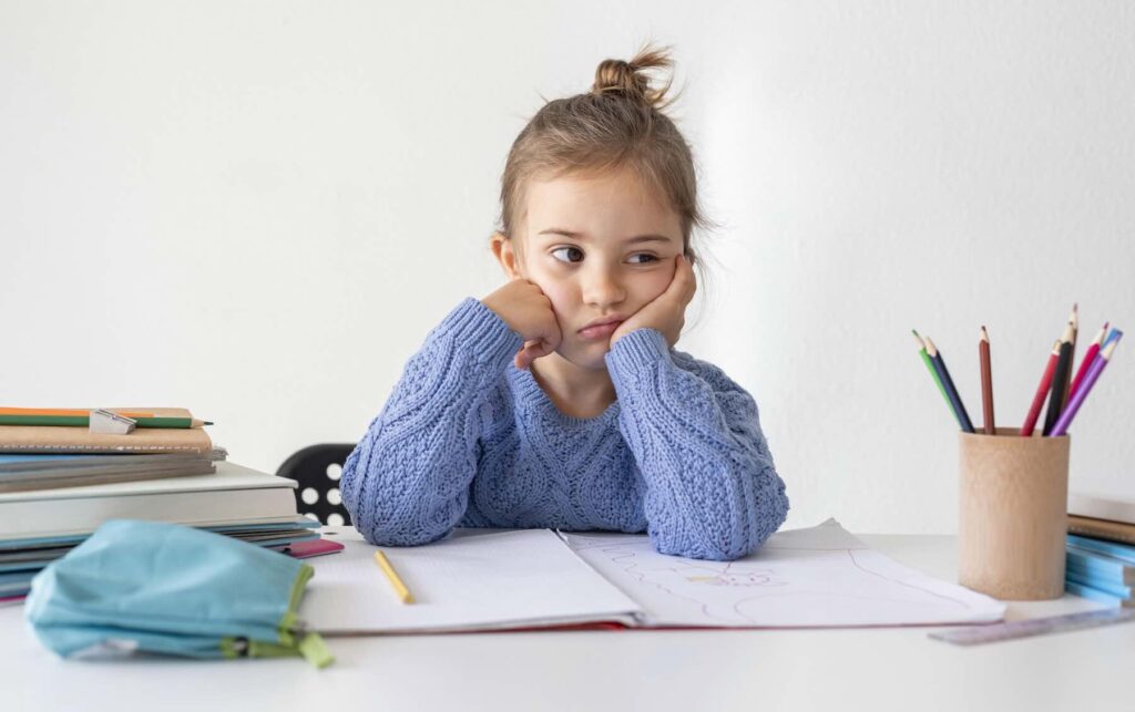 Girl bored with homework / Freepik