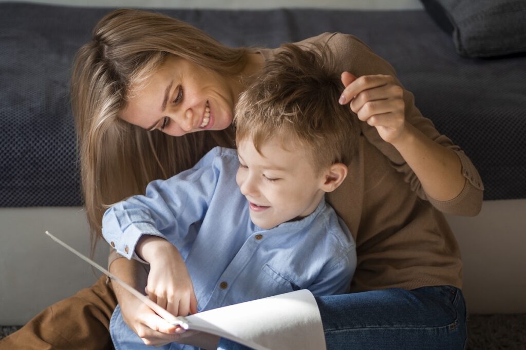 Мама и сын читают книгу сидя на полу