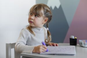 Девочка сидит за столом и пишет в тетради