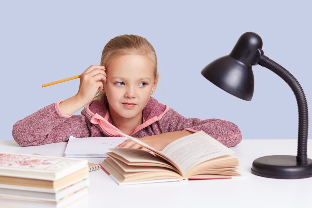 Ребенок сидит за книжкой и тетрадкой