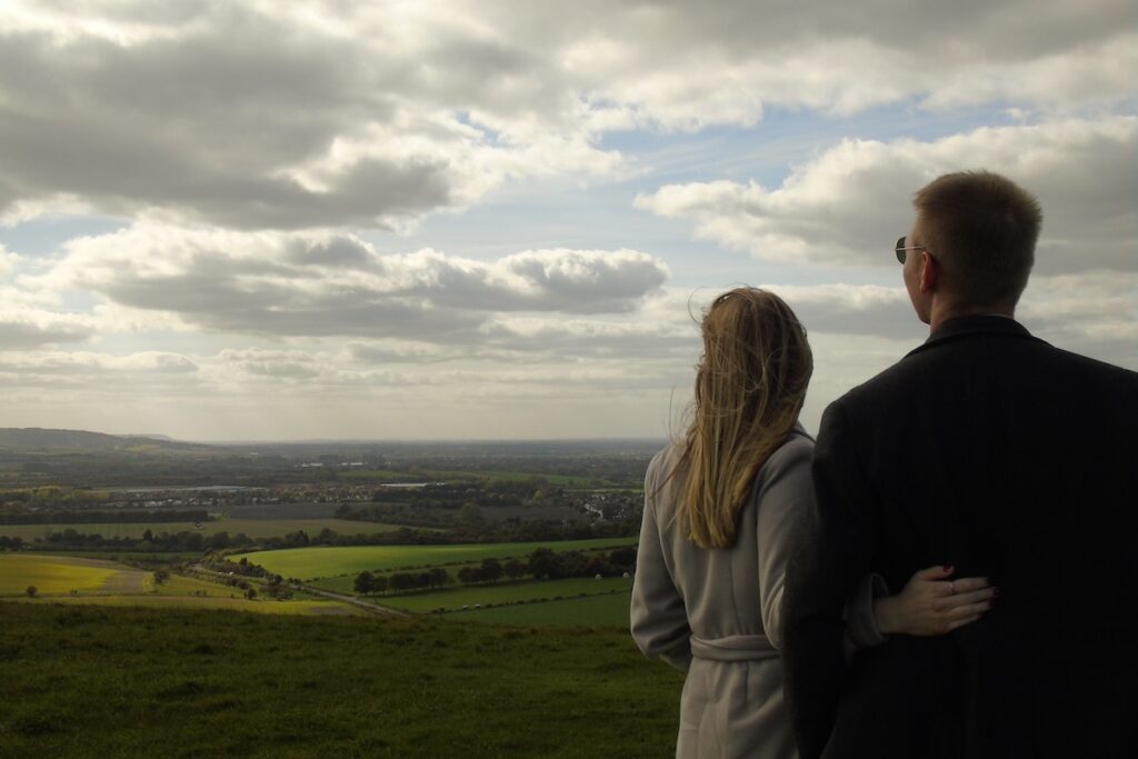 Парень и девушка стоят в лугах и смотрят на небо