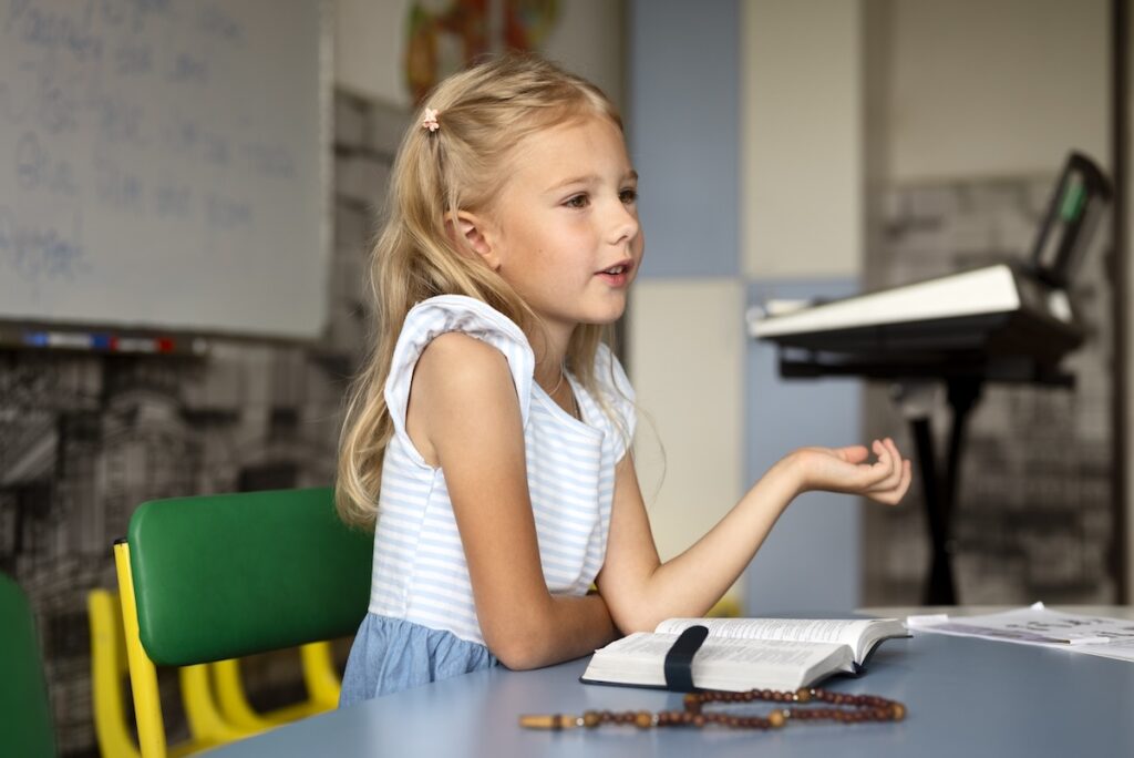 Девочка с книжкой за партой на уроке