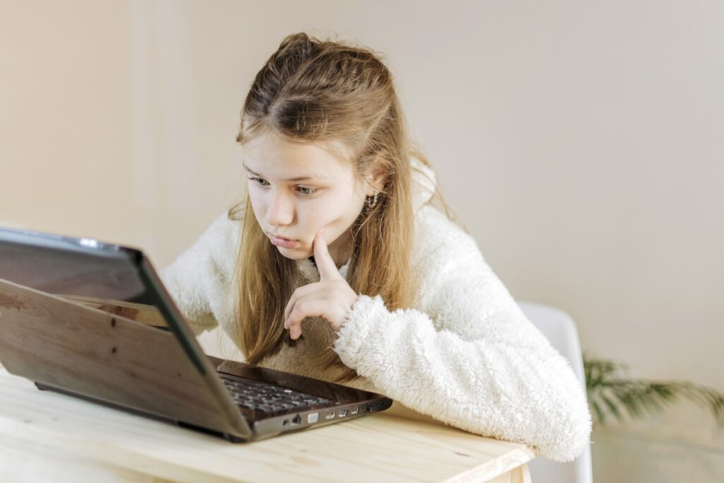 Сосредоточенная девочка учится онлайн