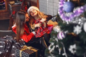 Beautiful mom in santa costume. Family with Christmas presents. Little girl on the bed.