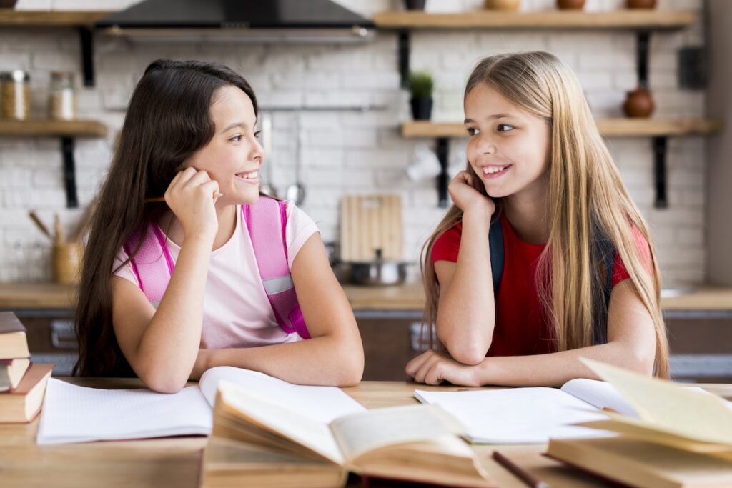 Девушки разговаривают в школе, сидя за партой