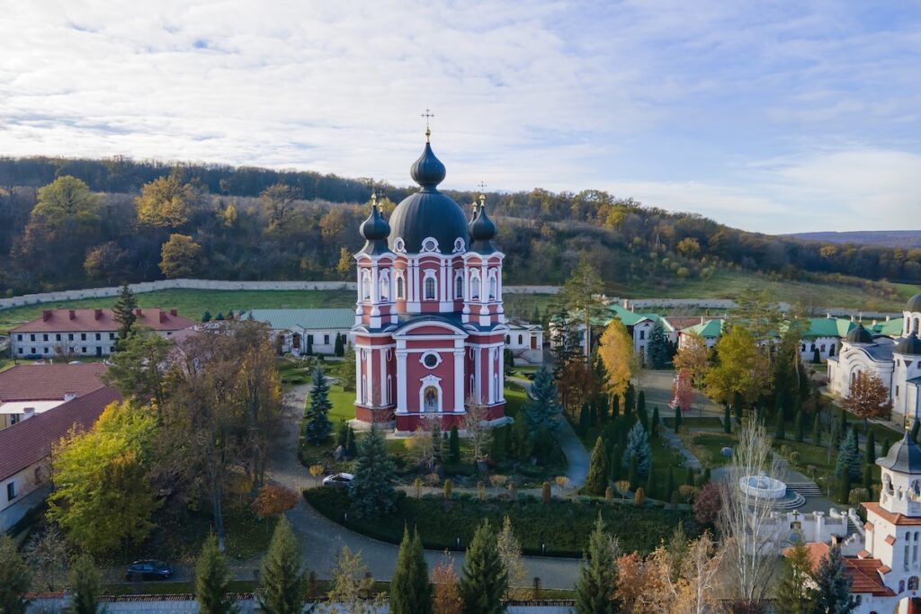 Вид на Курчинский монастырь с дрона. Церкви, другие здания, зеленые лужайки и пешеходные дорожки. Холмы, покрытые зеленью, вдали. Молдова