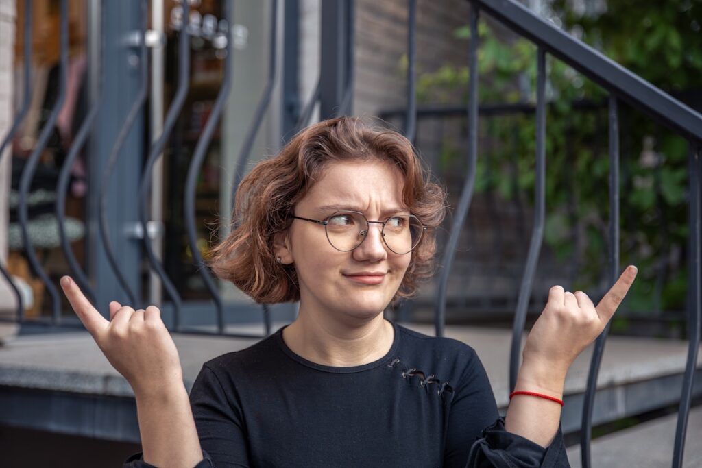 Женщина в очках показывает два пустых места для текста. Взвешивает все за и против. Фотография высокого качества. Молодая женщина делает выбор, выражая эмоции. Эмоциональная концепция.