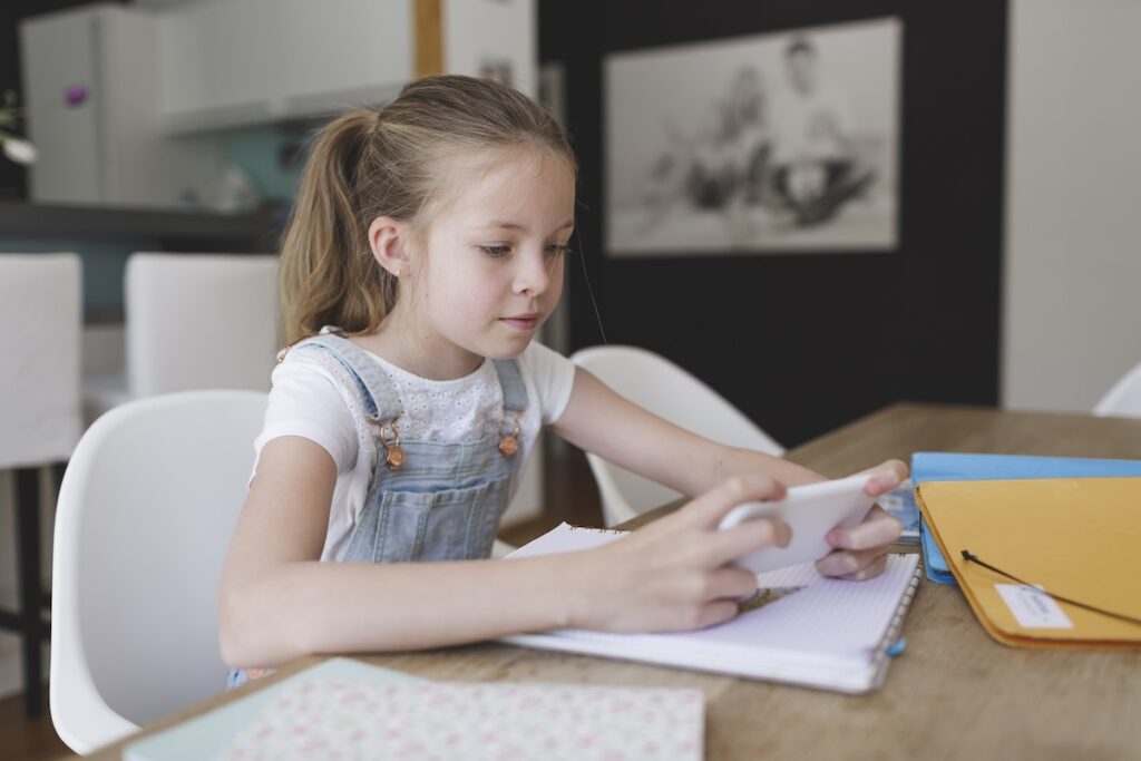 A Caucasian girl engages in language on her phone at home.