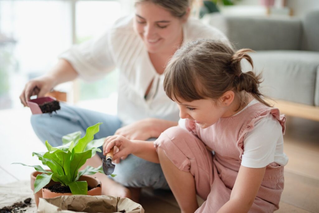 Мама и дочка сажают растение