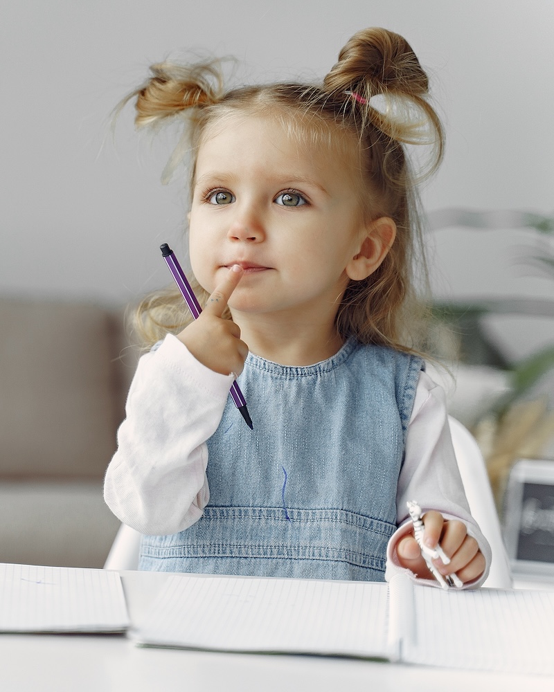 Ребенок с книгами. Девочка сидит на столе. Ребенок в классе.