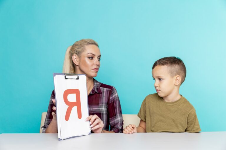 Mother helps son with homework on isolated pink background. Remote learning.