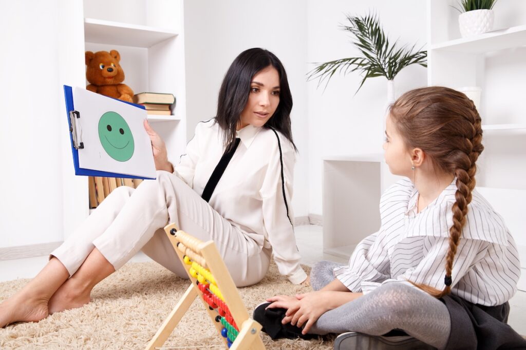 Концепция сеанса психотерапии. Женщина-психолог работает с милым маленьким ребенком.