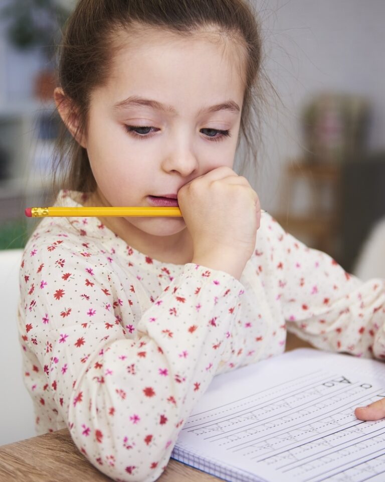 Сосредоточенная девочка делает домашнее задание дома