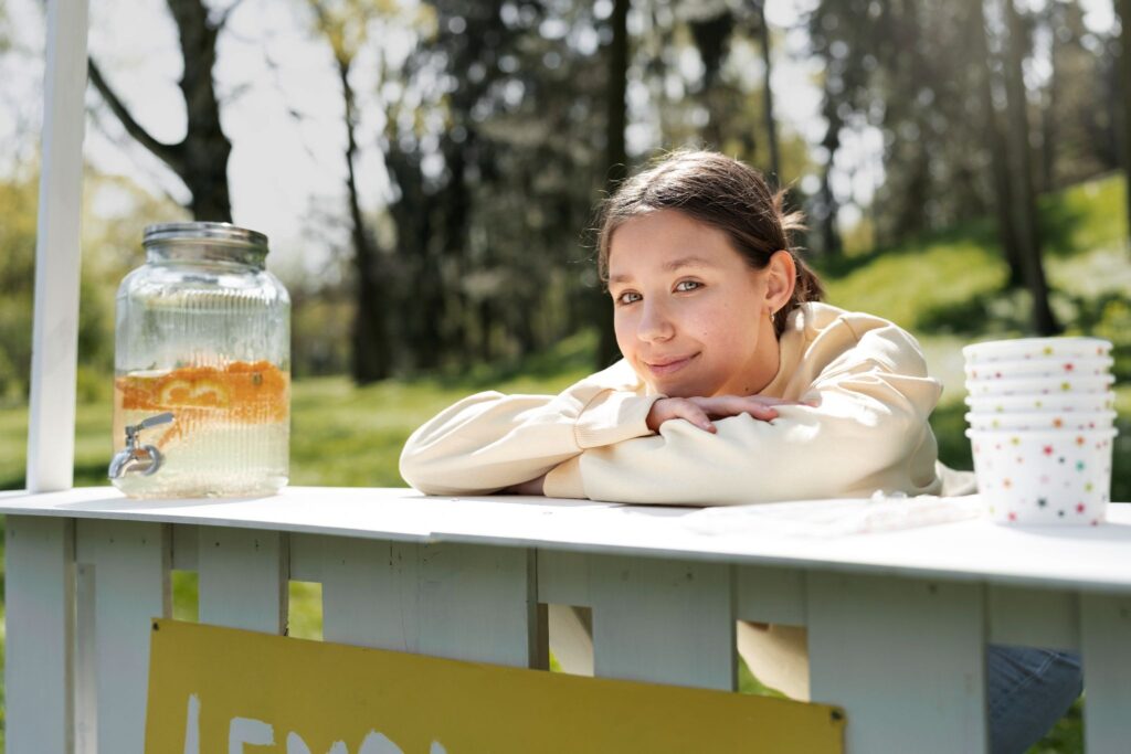 A girl at a table on the street with lemonade