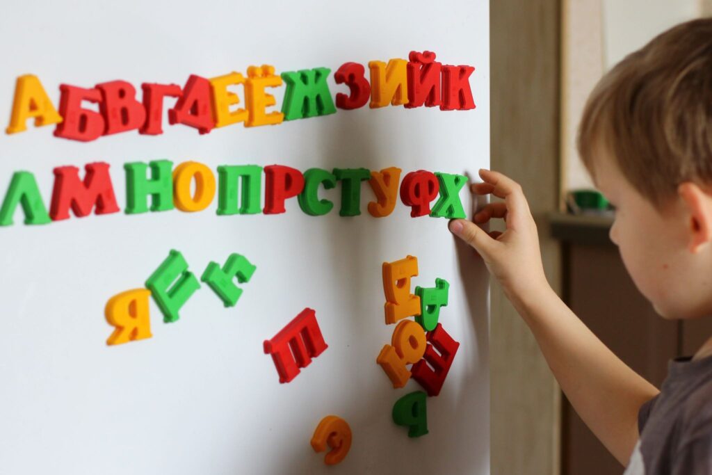 Мальчик раскладывает буквы на холодильнике