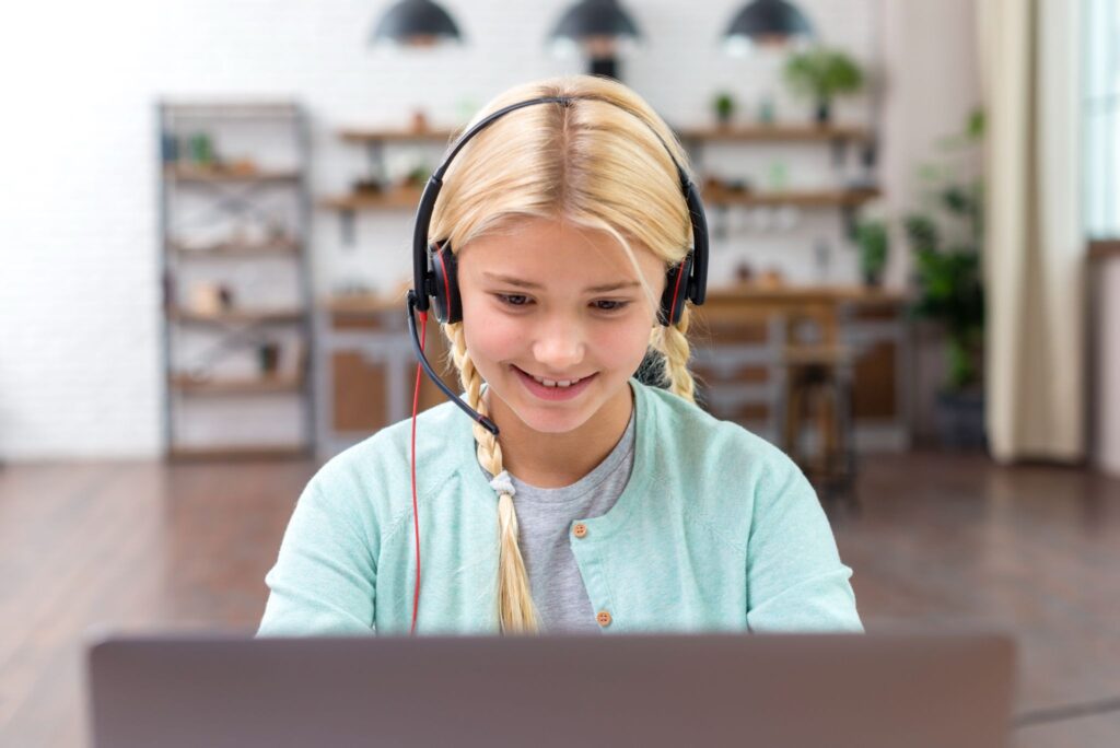 Девочка в наушниках за ноутбуком