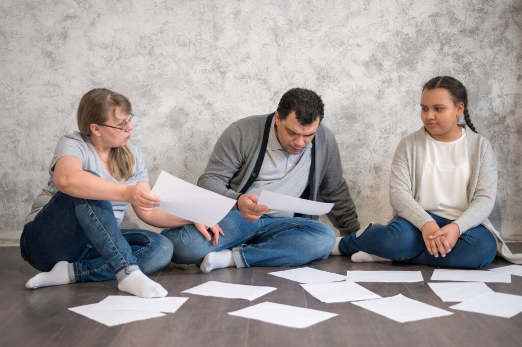 Мама, папа и девочка сидят на полу среди бумаг