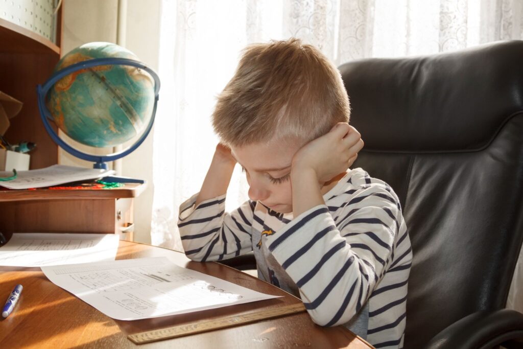 Мальчик сидит за столом и смотрит на бумагу