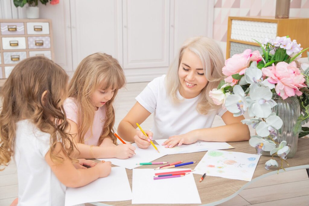 Мама и 2 девочек за столом рисуют