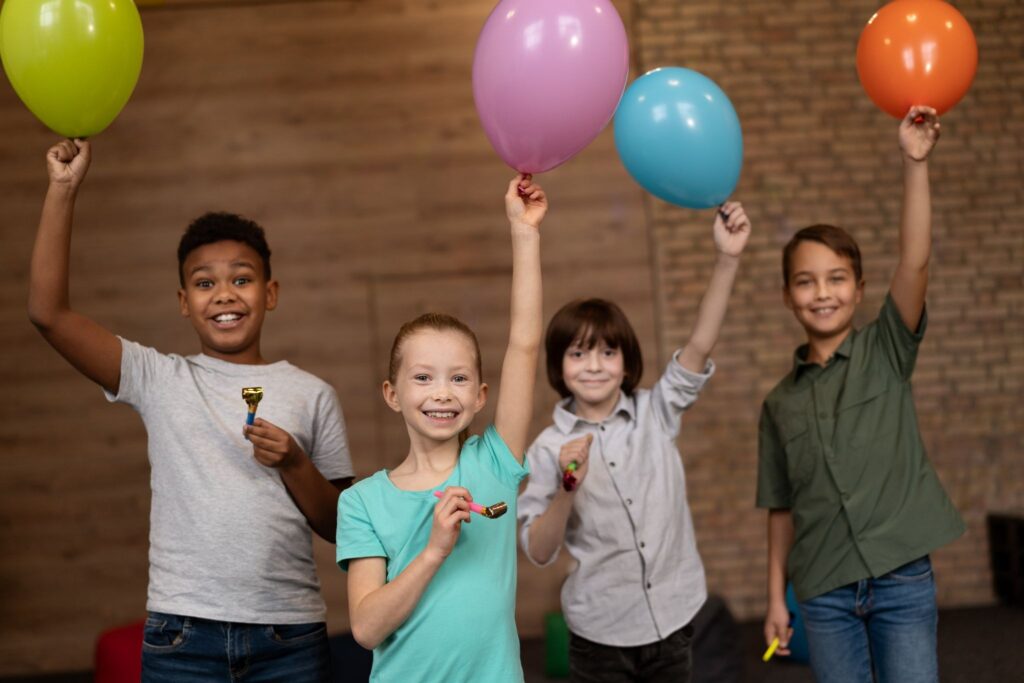 Четверо детей улыбаются и держат воздушные шары