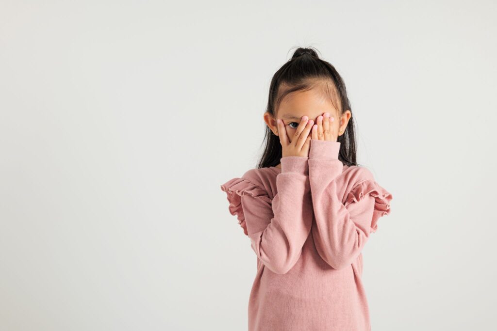 Девочка закрывает лицо руками