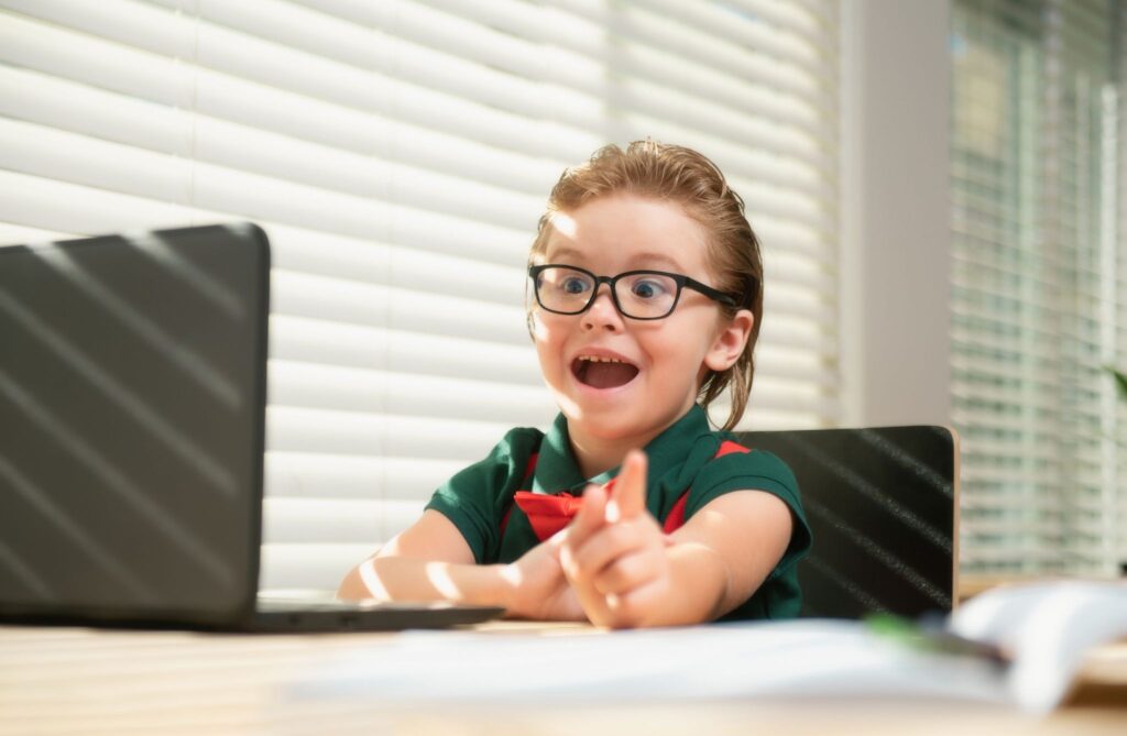 Мальчик в очках что-то говорит в экран ноцтбука