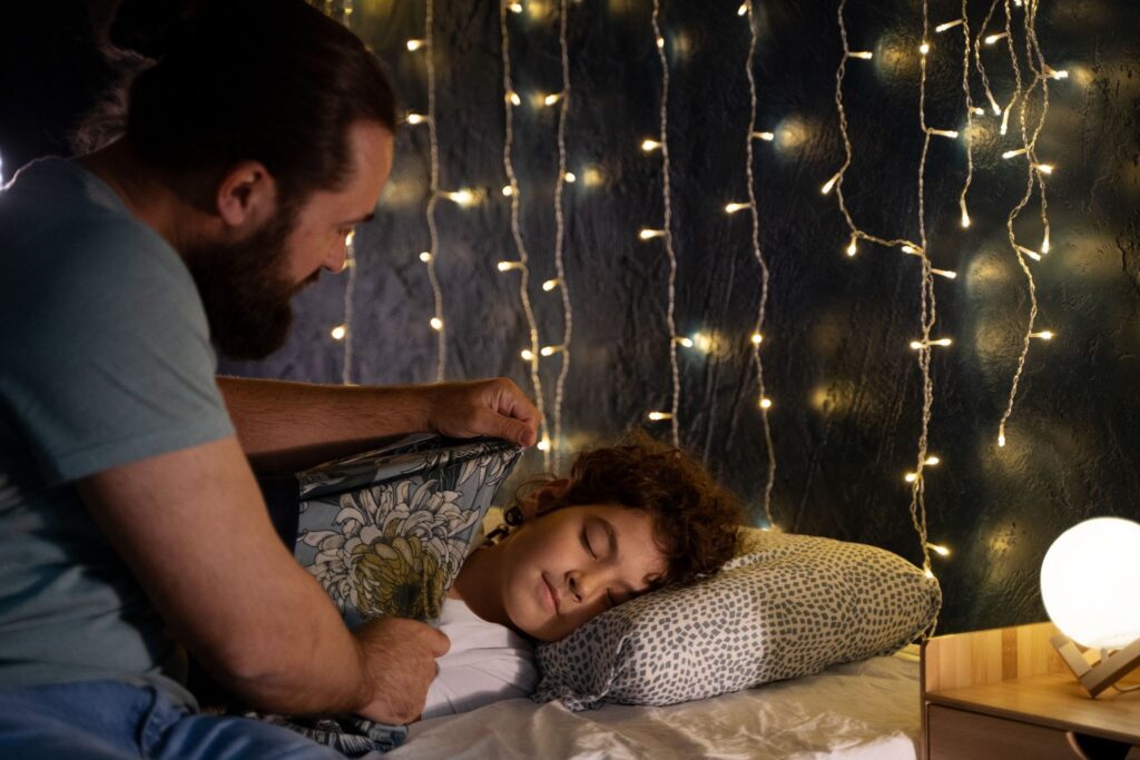 Папа поправляет одеяло спящему мальчику