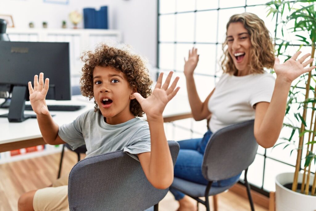 Мама и мальчик сидят на стульях, руки подняты