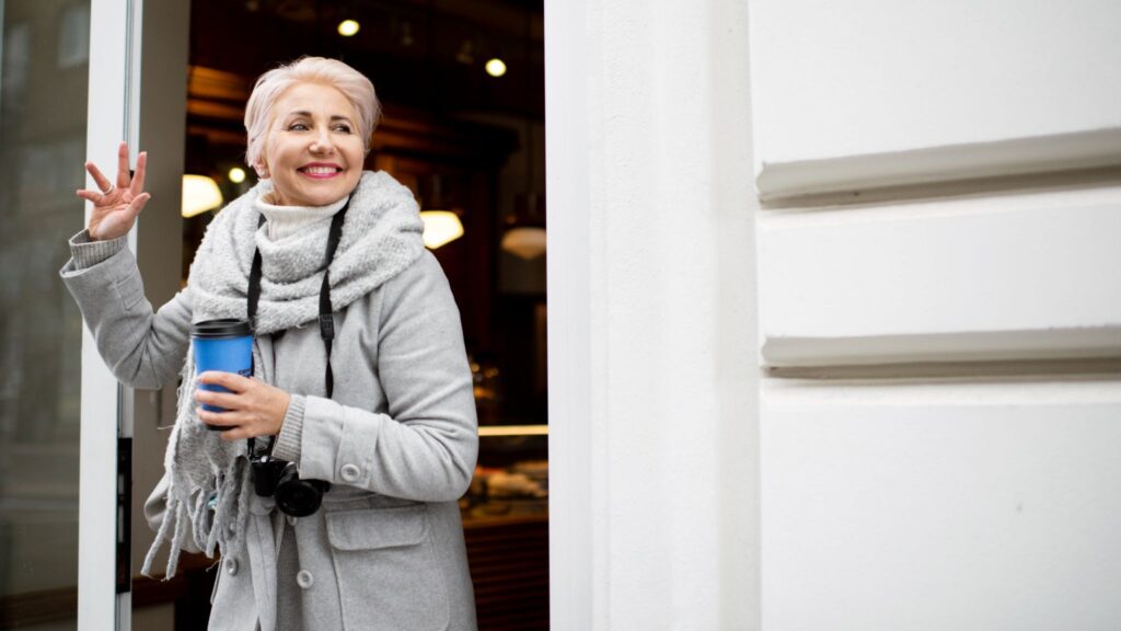 Женщина со стаканчиком в руке машет