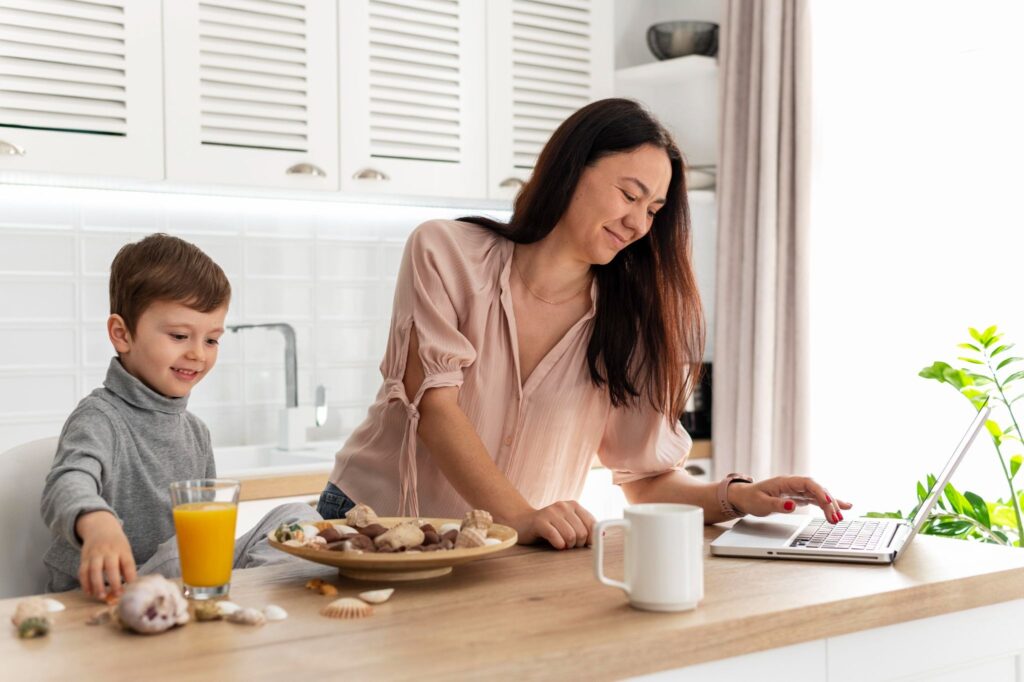 Мама смотрит в ноутбук, мальчик рядом с соком
