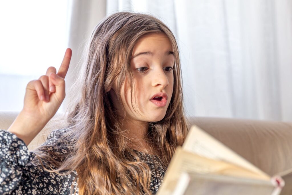 Девочка произносит звук, смотрит в книгу и поднимает палец вверх