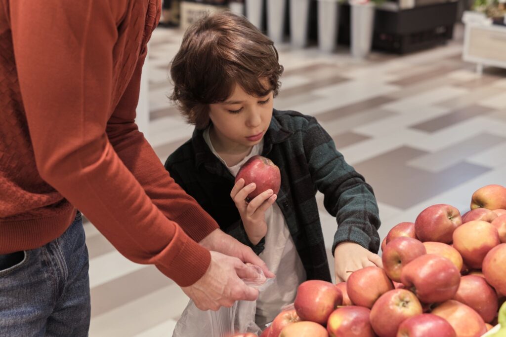 Мальчик складывает в пакет яблоки