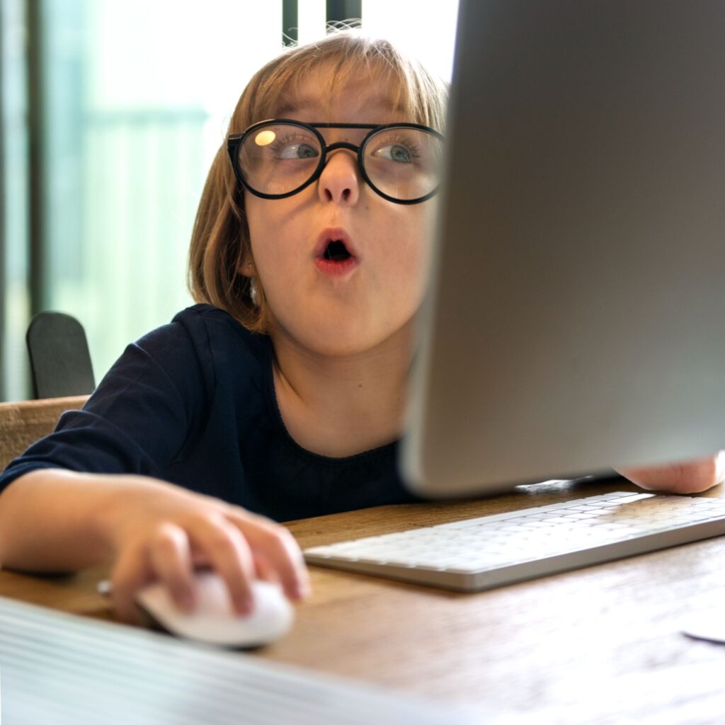 Мальчик в очках перед ноутбуком, в руке мышка, лицо удивленное