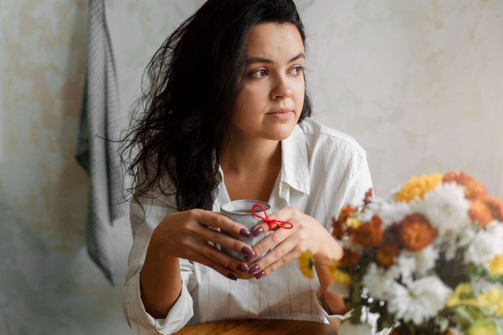 Девушка задумчивая с чашкой в руках смотрит в сторону