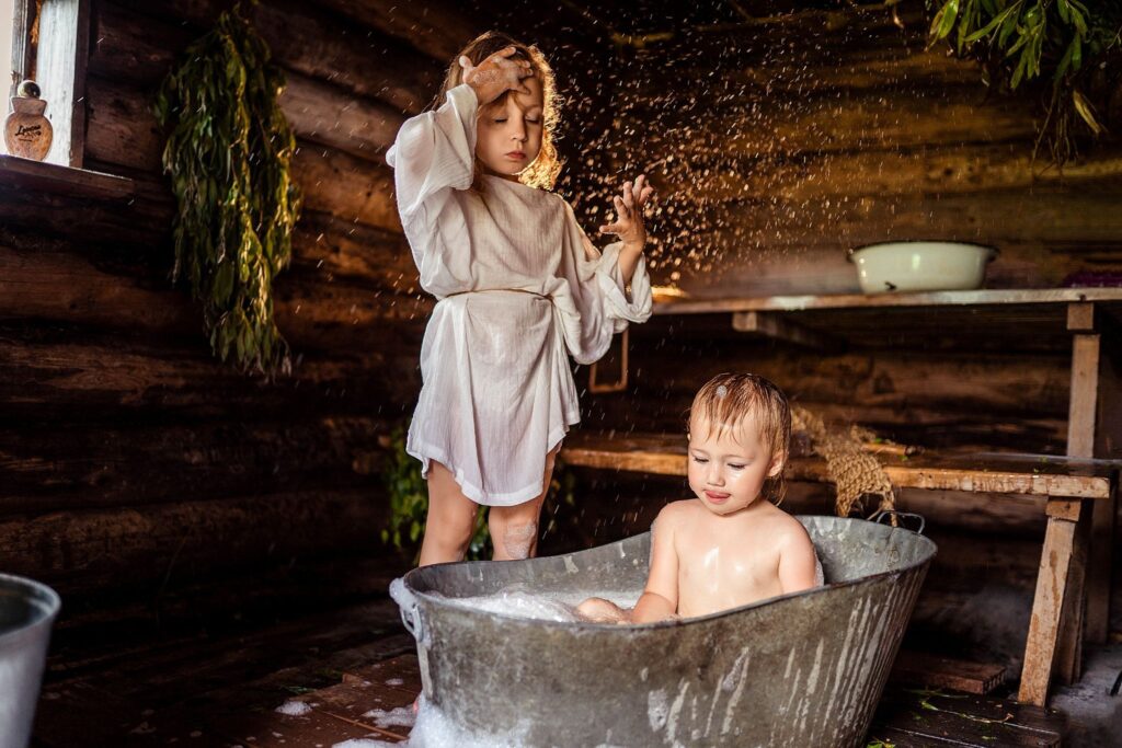 Баня, девочка стоит, малыш в железной ванне купается