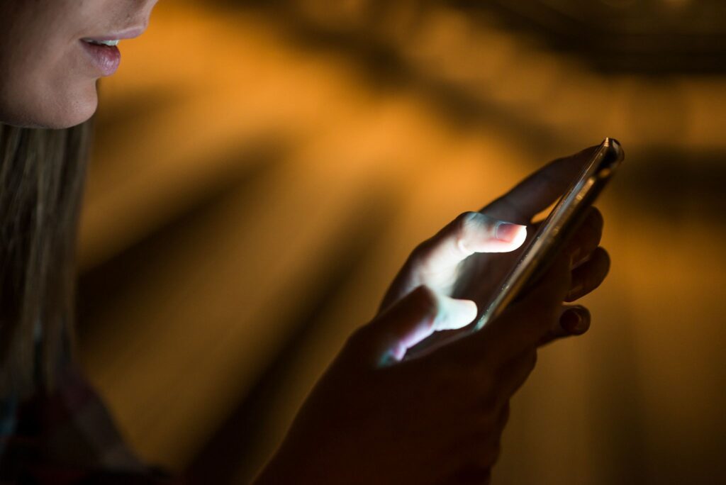 A girl in the dark looks at her mobile phone screen