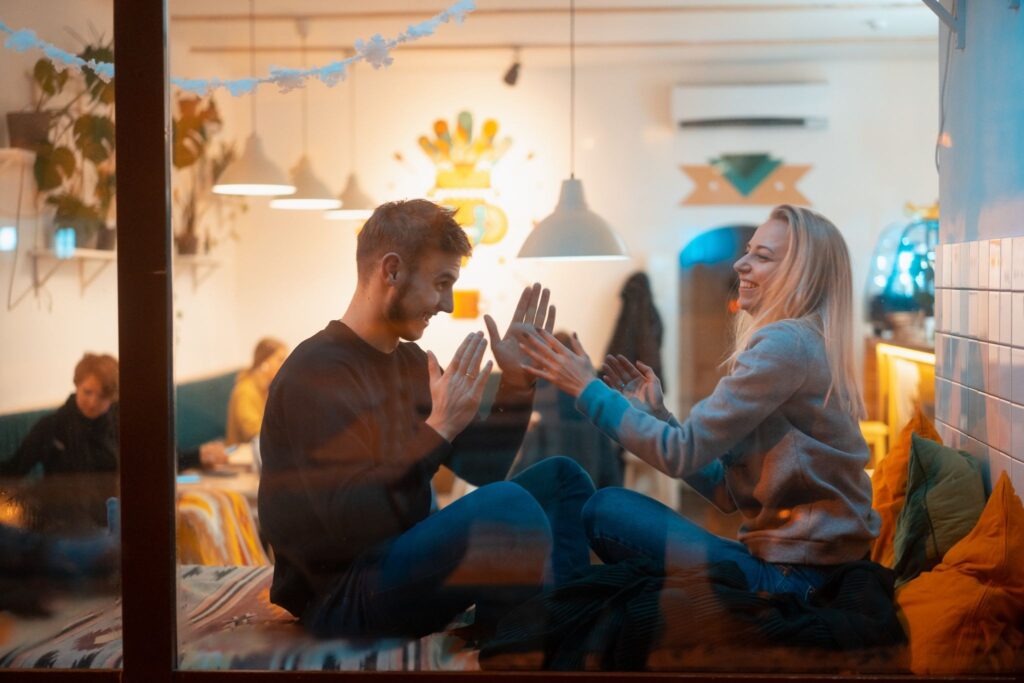 A man and a woman outside the window are reaching for each other.